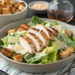 Grilled chicken Caesar salad with romaine lettuce, Parmesan cheese, and croutons served in a ceramic bowl.